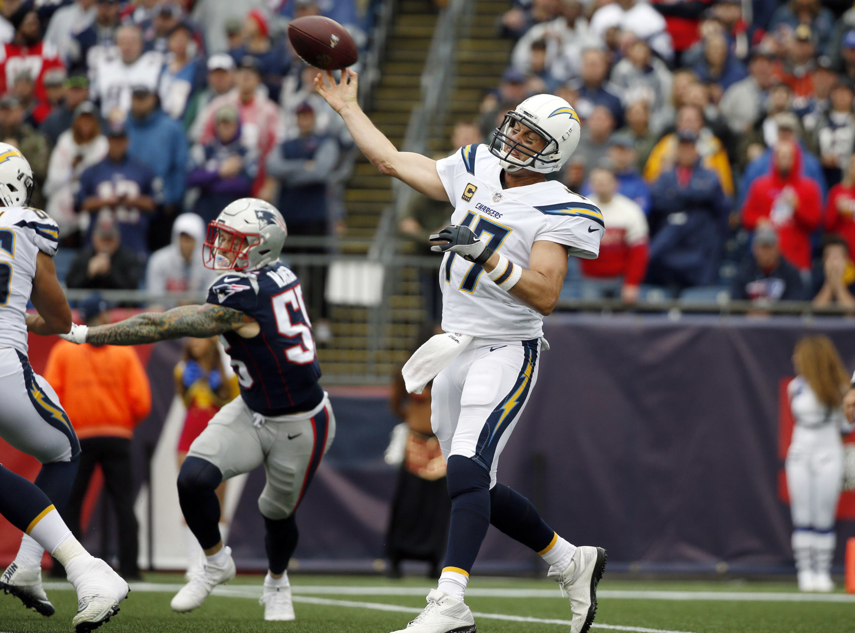 Los Angeles Chargers quarterback Philip Rivers (17) passes under pressure from New England Patriots defensive end Cassius Marsh (55) during the first half of an NFL football game, Sunday, Oct. 29, 2017, in Foxborough, Mass. (AP Photo/Michael Dwyer)