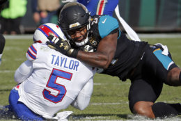 FILE - In this Jan. 7, 2018, file photo, Jacksonville Jaguars defensive end Yannick Ngakoue, right, draws a penalty by hitting Buffalo Bills quarterback Tyrod Taylor (5) with helmet-to-helmet contact during the first half of an NFL wild-card playoff football game in Jacksonville, Fla. The NFL’s new rule making it a penalty when a player leads with his helmet is generating plenty of grumbling about taking the football out of the sport, but more practically it’s led to confusion about how it’ll be enforced.  (AP Photo/Stephen B. Morton, File)