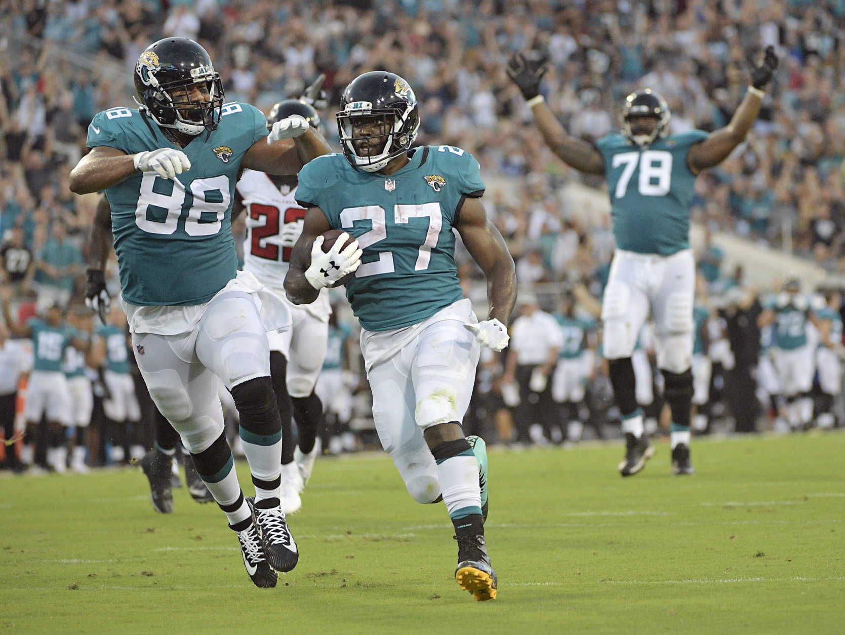 Jacksonville Jaguars running back Leonard Fournette (27) runs for a 21-yard touchdown against the Atlanta Falcons, next to tight end Austin Seferian-Jenkins (88), as offensive tackle Jermey Parnell (78) signals the score during the first half of an NFL preseason football game Saturday, Aug. 25, 2018, in Jacksonville, Fla. (AP Photo/Phelan M. Ebenhack)