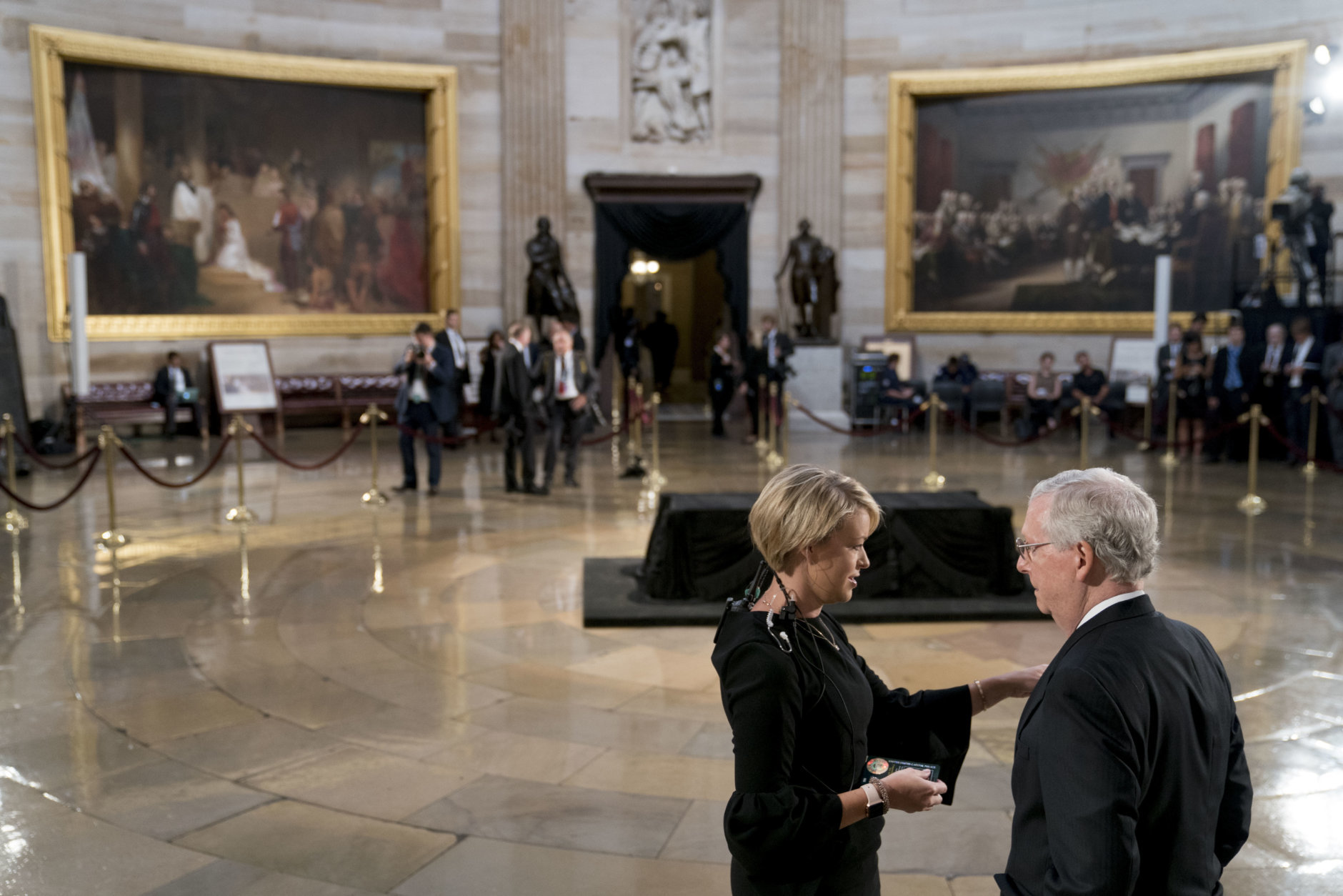 Senate Majority Leader Mitch McConnell of Ky., right, speaks to an aide before the casket of Sen. John McCain, R-Ariz., lies in state in the Rotunda of the U.S. Capitol, Friday, Aug. 31, 2018, in Washington. (AP Photo/Andrew Harnik, Pool)