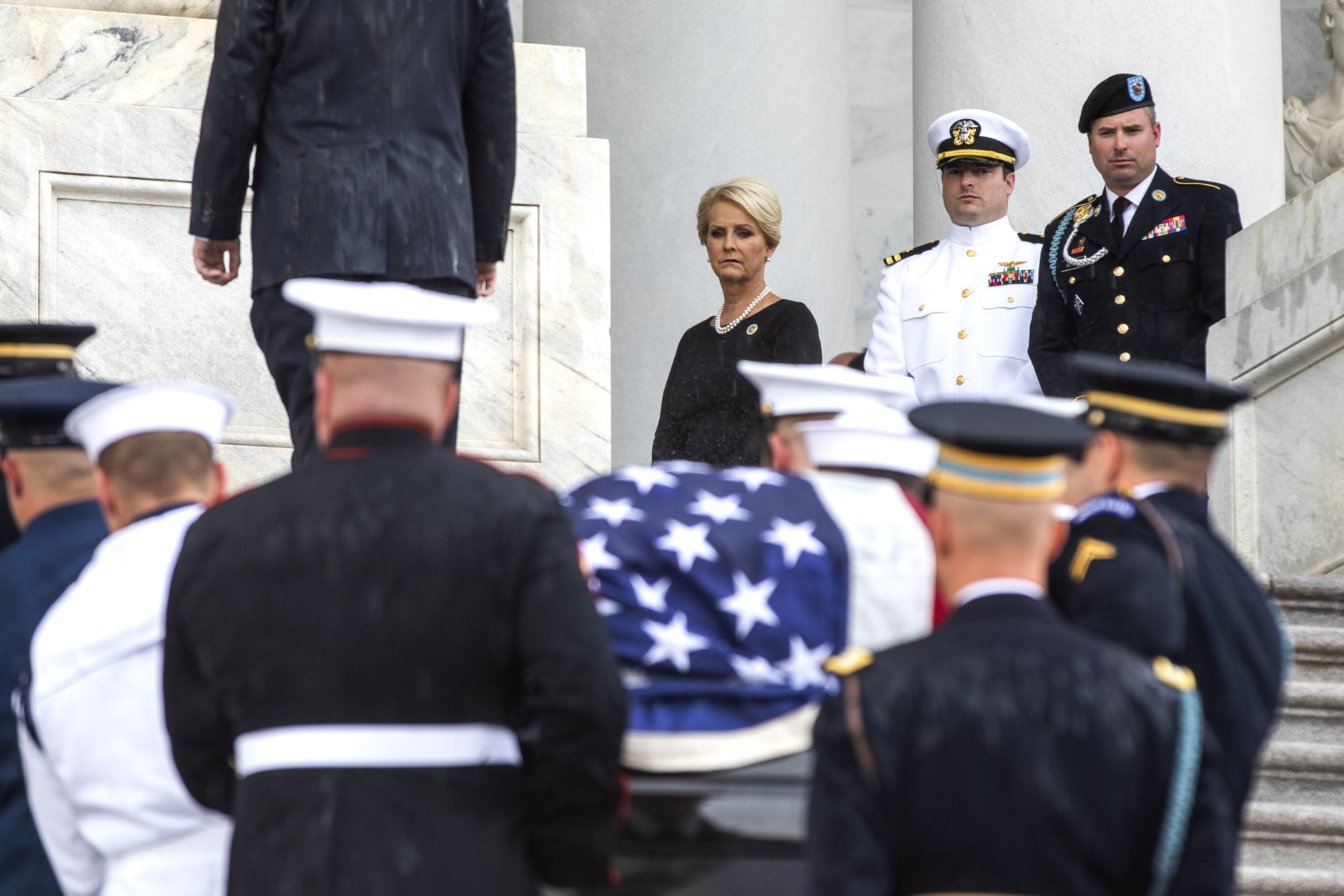 The flag-draped casket of Sen. John McCain, R-Ariz., is carried up the steps of the U.S. Capitol, Friday, Aug. 31, 2018, in Washington as Cindy McCain, top right, joined by her sons Jack McCain, and James McCain, look on. (Jim Lo Scalzo/Pool Photo via AP)