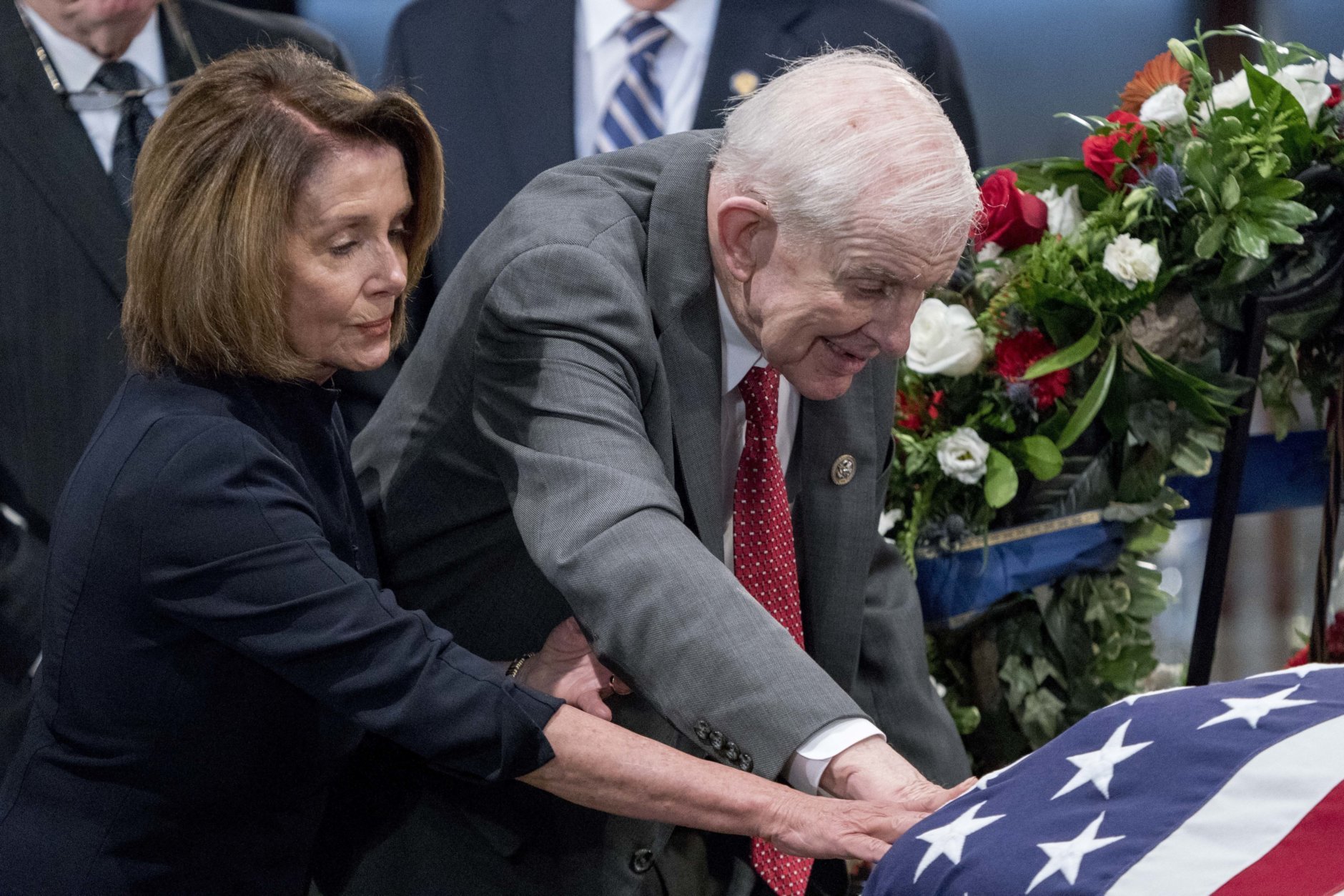 House Minority Leader Nancy Pelosi of Calif., left, and Rep. Sam Johnson, R-Texas, right, touch the casket of Sen. John McCain, R-Ariz., as he lies in state in the Rotunda of the U.S. Capitol, Friday, Aug. 31, 2018, in Washington. (AP Photo/Andrew Harnik, Pool)