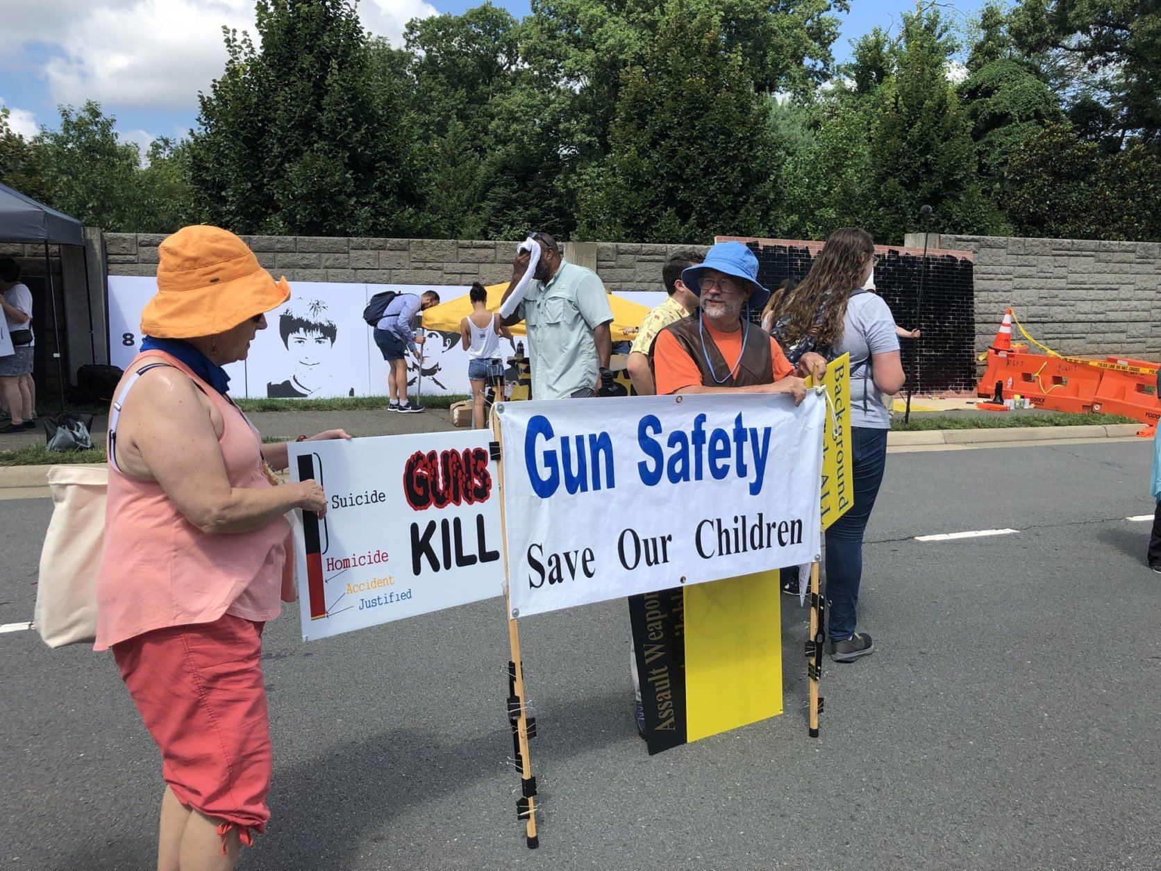 Protesters holding banners on Waples Mill Road, near the NRA's headquaters in Fairfax. (WTOP/Melissa Howell)