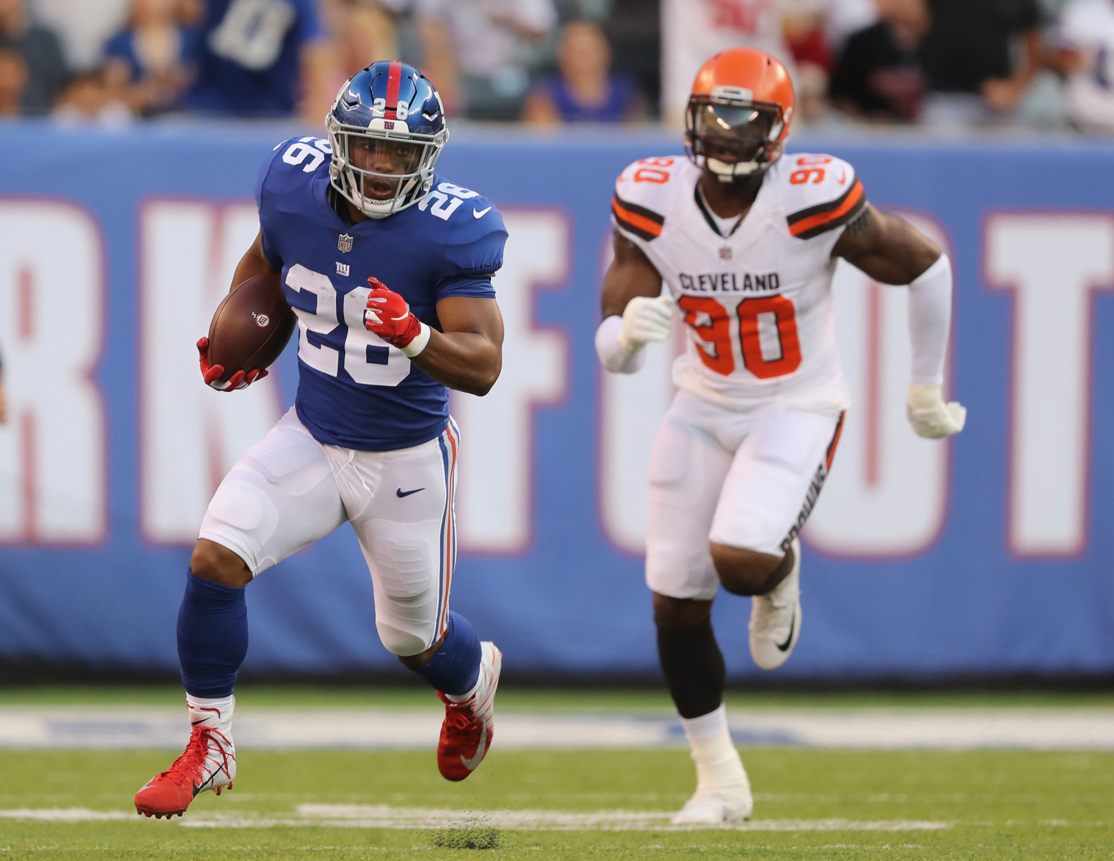 EAST RUTHERFORD, NJ - AUGUST 09:  Saquon Barkley #26 of the New York Giants carries the ball as Emmanuel Ogbah #90 of the Cleveland Browns in the first quarter during their preseason game on August 9,2018 at MetLife Stadium in East Rutherford, New Jersey.  (Photo by Elsa/Getty Images)