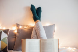 Young women relaxing in bad while reading book and enjoying in decorative light