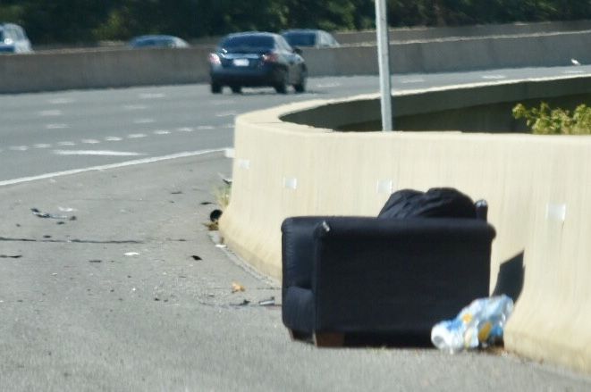 A couch rests on the shoulder of Interstate 295 in the District. Furniture tied with metal objects for the third most common form of debris on D.C. area highways. (WTOP/Dave Dildine)