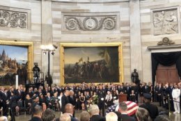 Senators Mitch McConnell and Chuck Schumer lay a wreath at John McCain's casket in the Capitol Rotunda. (WTOP/Chris Cioffi)