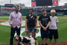 Smoke with Sam Wolbert, of the Animal Welfare League of Arlington, at left, and his new family at Nationals Park. (Courtesy Animal Welfare League of Arlington)