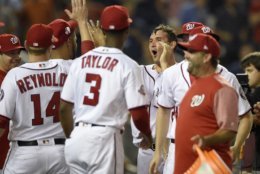 Washington Nationals' Ryan Zimmerman, right center, celebrates his walk-off two-run home run with Michael Taylor (3), Mark Reynolds (14) and others in a baseball game against the Philadelphia Phillies, Wednesday, Aug. 22, 2018, in Washington. The Nationals won 8-7. (AP Photo/Nick Wass)