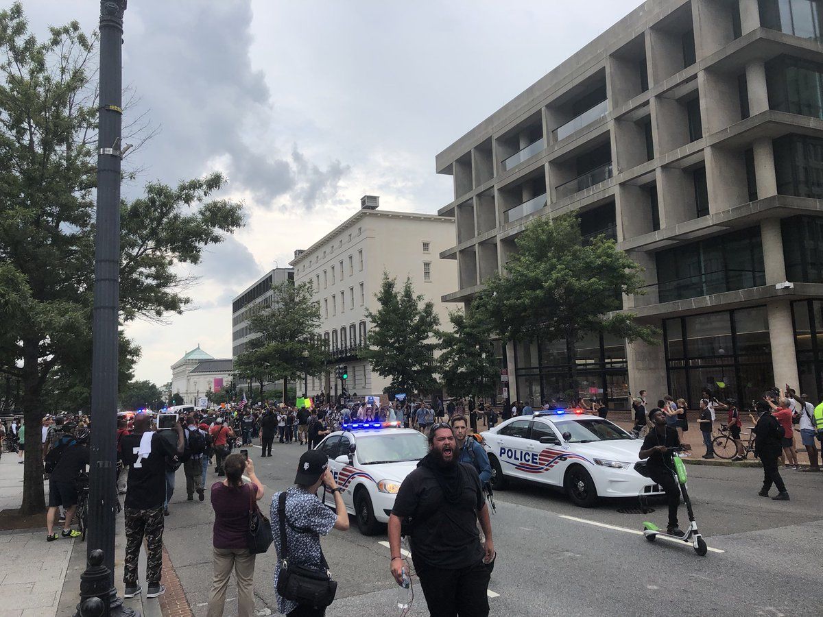 Counterprotesters walk in front of the group of Unite The Right protesters. They are mostly surrounded by D.C. Police. (WTOP/Max Smith)