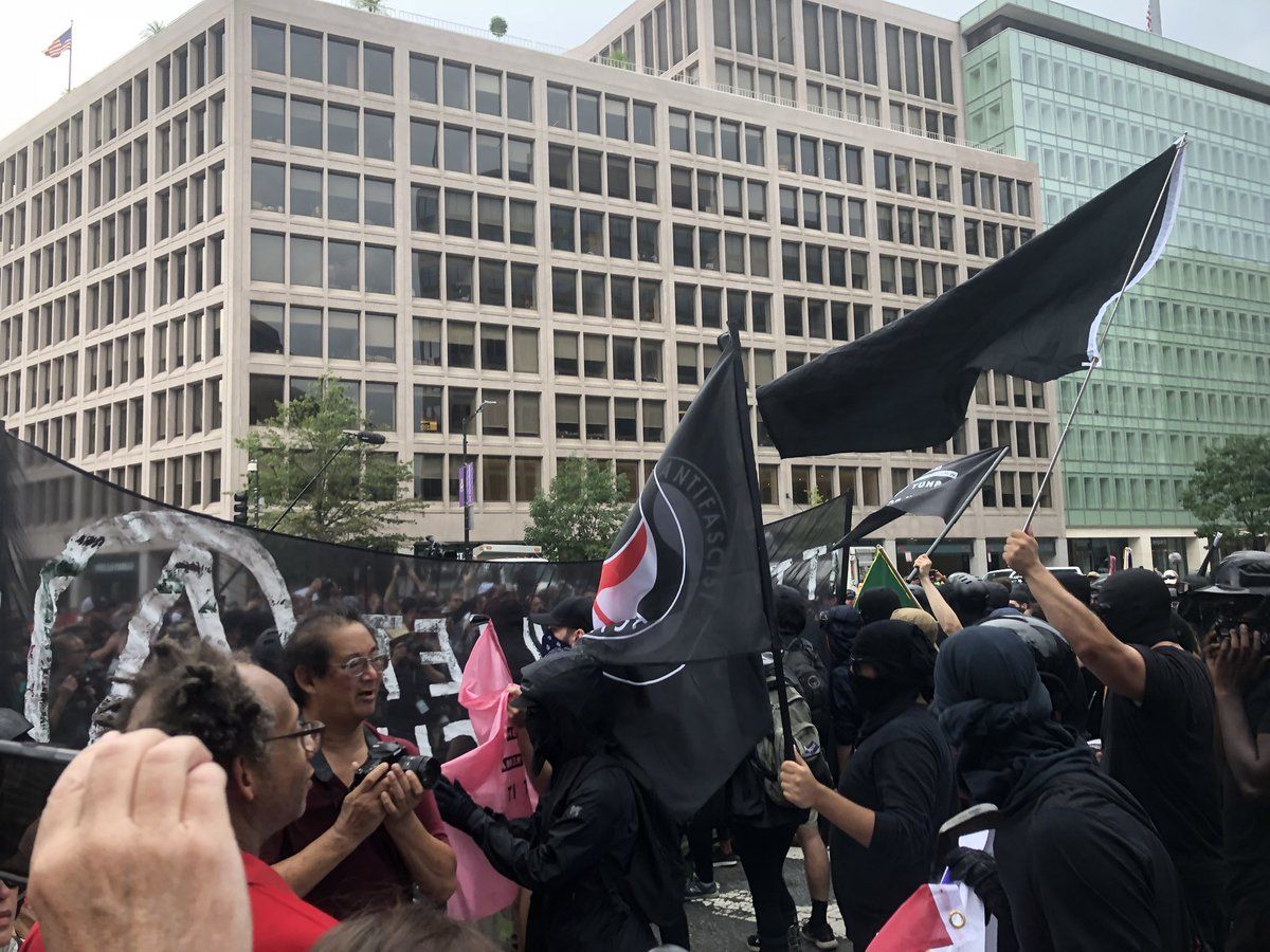 Counterprotesters walk in front of the group of Unite The Right protesters. The protesters are mostly surrounded by D.C. Police. (WTOP/Max Smith)