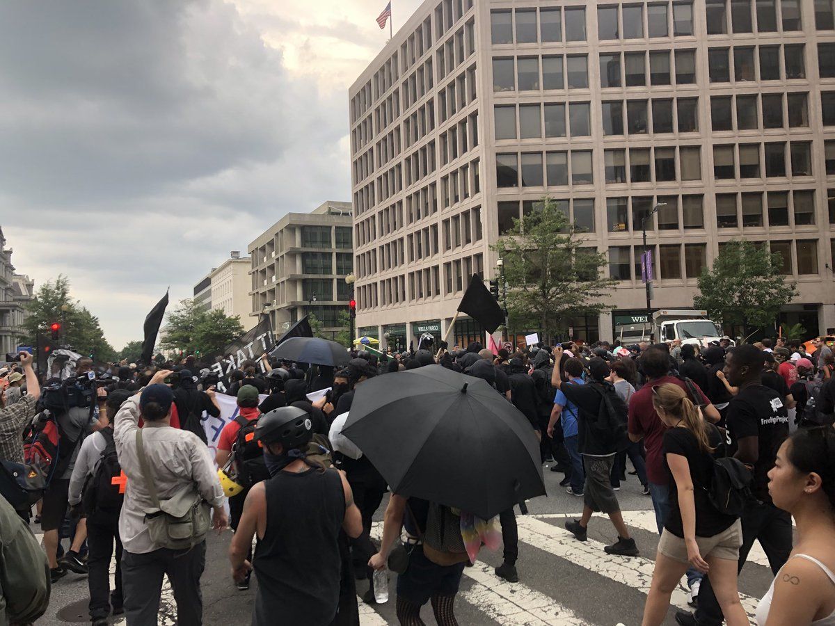 Counterprotesters walk in front of the group of Unite The Right protesters. The protesters are mostly surrounded by D.C. Police. (WTOP/Max Smith)