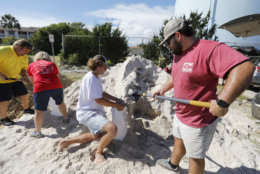 Walker Townsend, at right, from the Isle of Palms, S.C., fills a sand bag while Dalton Trout, in center, holds the bag at the Isle of Palms municipal lot where the city was giving away free sand in preparation for Hurricane Florence at the Isle of Palms S.C., Monday, Sept. 10, 2018. (AP Photo/Mic Smith)