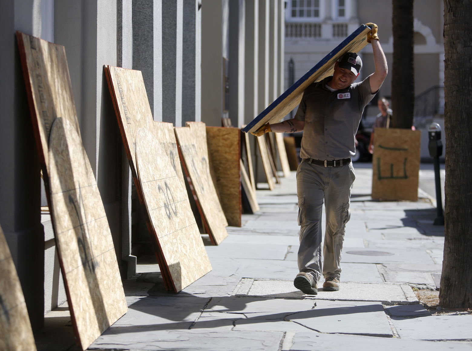 CORRECTS DATE  - Preston Guiher carries a sheet of plywood as he prepares to board up a Wells Fargo bank in preparation for Hurricane Florence in downtown Charleston, S.C., Tuesday, Sept. 11, 2018. (AP Photo/Mic Smith)