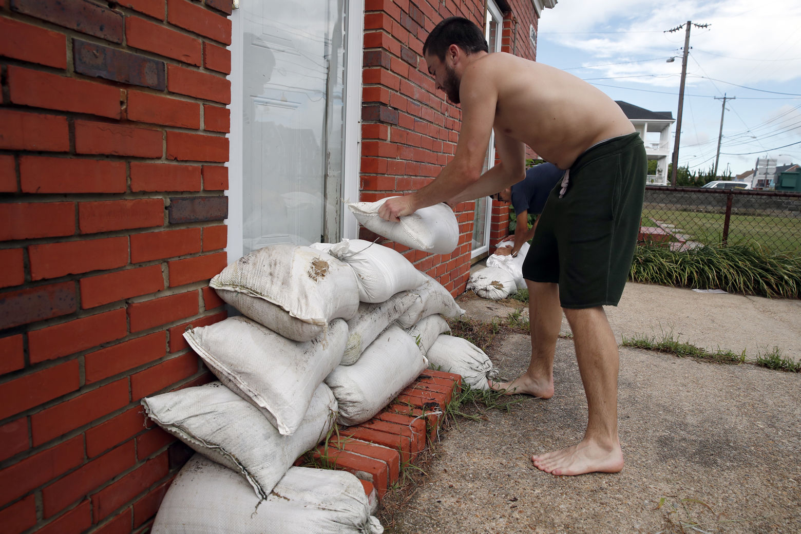 Adam Bazemore places sandbags in the doorways, Tuesday, Sept. 11, 2018, in the Willoughby Spit area of Norfolk, Va., as he makes preparations for Hurricane Florence. (AP Photo/Alex Brandon)