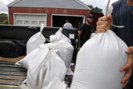 Seth Bazemore IV, center moves sandbags, Tuesday, Sept. 11, 2018, in the Willoughby Spit area of Norfolk, Va., as they make preparations for Hurricane Florence. (AP Photo/Alex Brandon)
