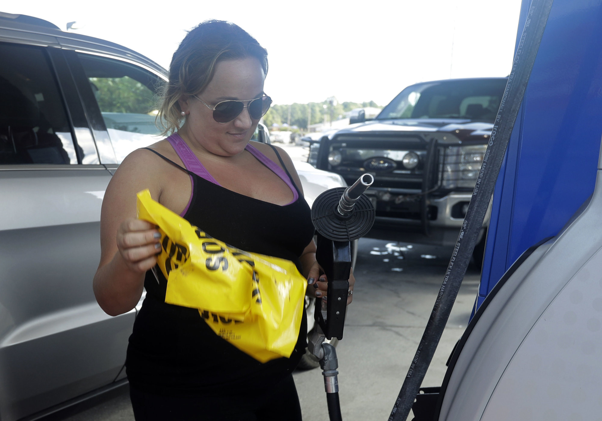 Sarah Dankanich, right, removes an "out of service" wrapper from a gas pump as her husband prepares to pump gas in cans in advance of Hurricane Florence in Wilmington, N.C., Wednesday, Sept. 12, 2018. Florence exploded into a potentially catastrophic hurricane Monday as it closed in on North and South Carolina, carrying winds up to 140 mph (220 kph) and water that could wreak havoc over a wide stretch of the eastern United States later this week. (AP Photo/Chuck Burton)