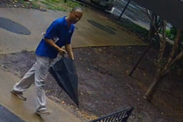 The suspect captured on surveillance video is described as black man, about 60 years, between 5 feet, 10 inches and 6 feet tall with a medium build. He has dark short curly hair with some gray. He was wearing a bright blue shirt, khaki pants, tan shoes and was carrying an umbrella at the time, police said. (Courtesy Arlington County police)