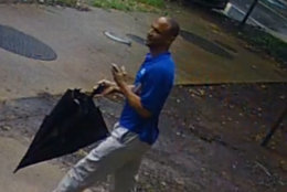 The suspect captured on surveillance video is described as black man, about 60 years, between 5 feet, 10 inches and 6 feet tall with a medium build. He has dark short curly hair with some gray. He was wearing a bright blue shirt, khaki pants, tan shoes and was carrying an umbrella at the time, police said. (Courtesy Arlington County police)