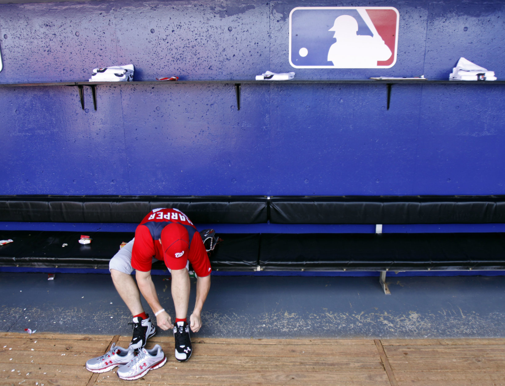 Washington Nationals' Bryce Harper ties his shoe in the dugout before the start of a spring training baseball game against the New York Mets Monday, Feb. 28, 2011, in Port St. Lucie, Fla. (AP Photo/Jeff Roberson)