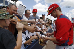 Washington Nationals top prospect Bryce Harper signs autographs for fans before the start of the the Nationals  spring training baseball game against the New York Yankees at Steinbrenner Field in Tampa, Fla., Friday, March 16, 2012.  (AP Photo/Kathy Willens)