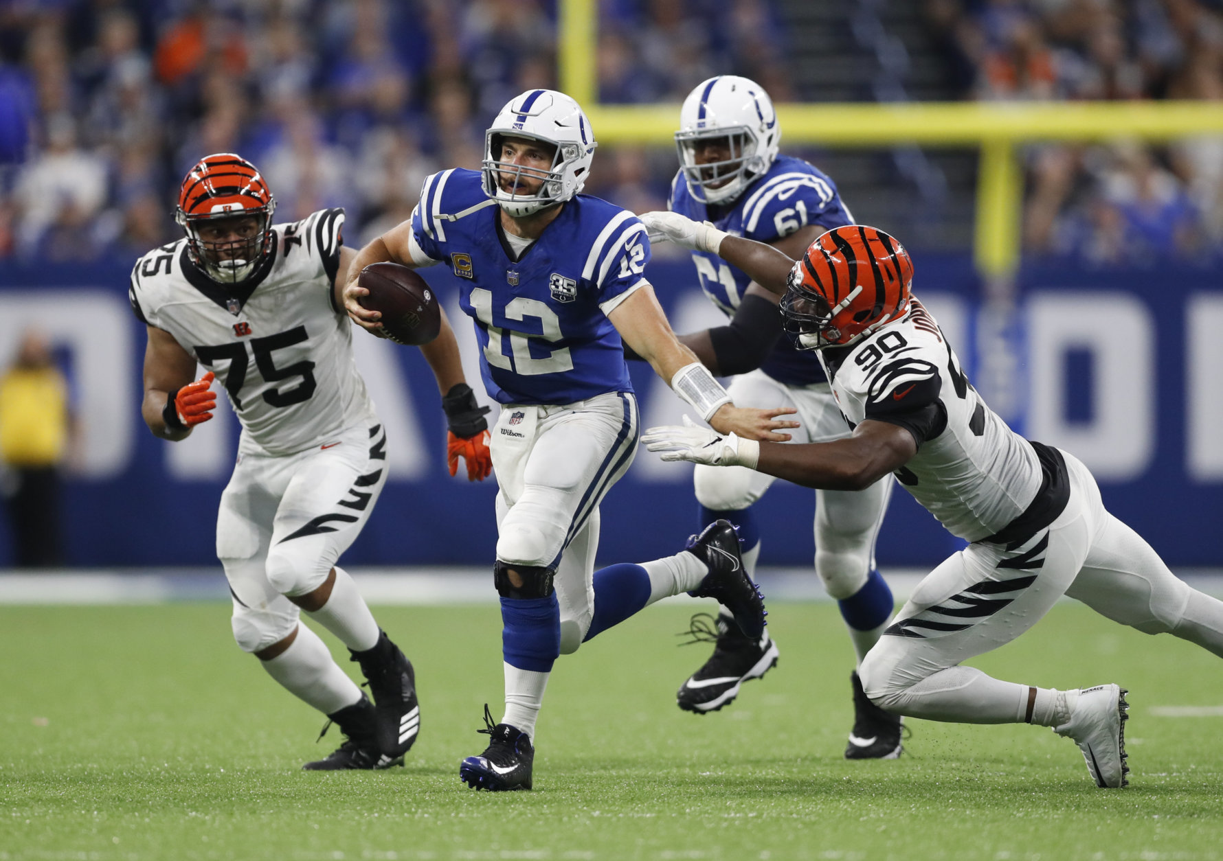 Indianapolis Colts quarterback Andrew Luck (12) is chased by Cincinnati Bengals defensive end Jordan Willis (75) and defensive end Michael Johnson (90) during the second half of an NFL football game in Indianapolis, Sunday, Sept. 9, 2018. The Bengals defeated the Colts 34-23. (AP Photo/Jeff Roberson)