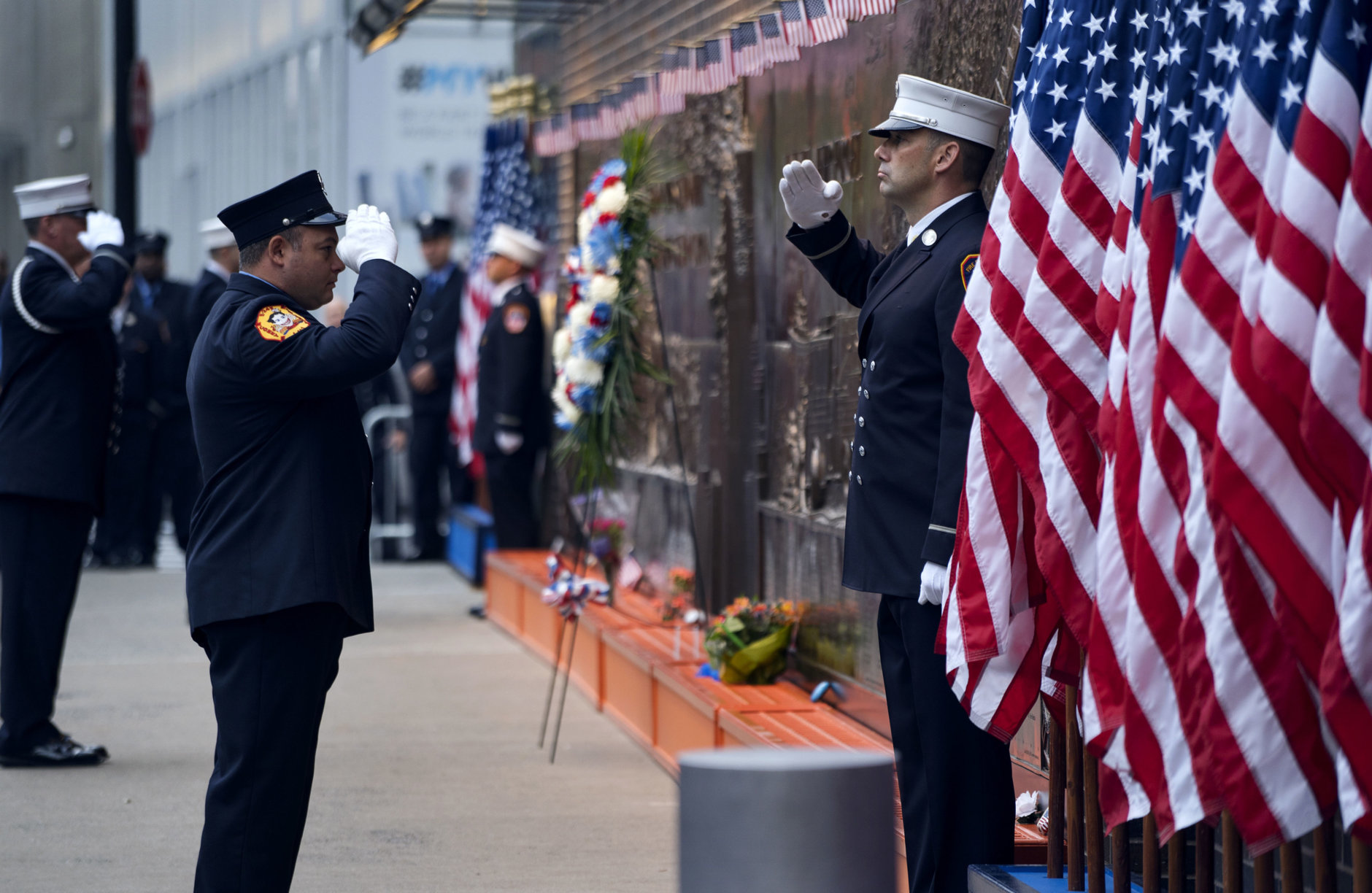 New York City firefighters salute in front of a memorial on the side of a firehouse adjacent to One World Trade Center and the 9/11 Memorial site during ceremonies on the anniversary of 9/11 terrorist attacks in New York on Tuesday, Sept. 11, 2018. (AP Photo/Craig Ruttle)