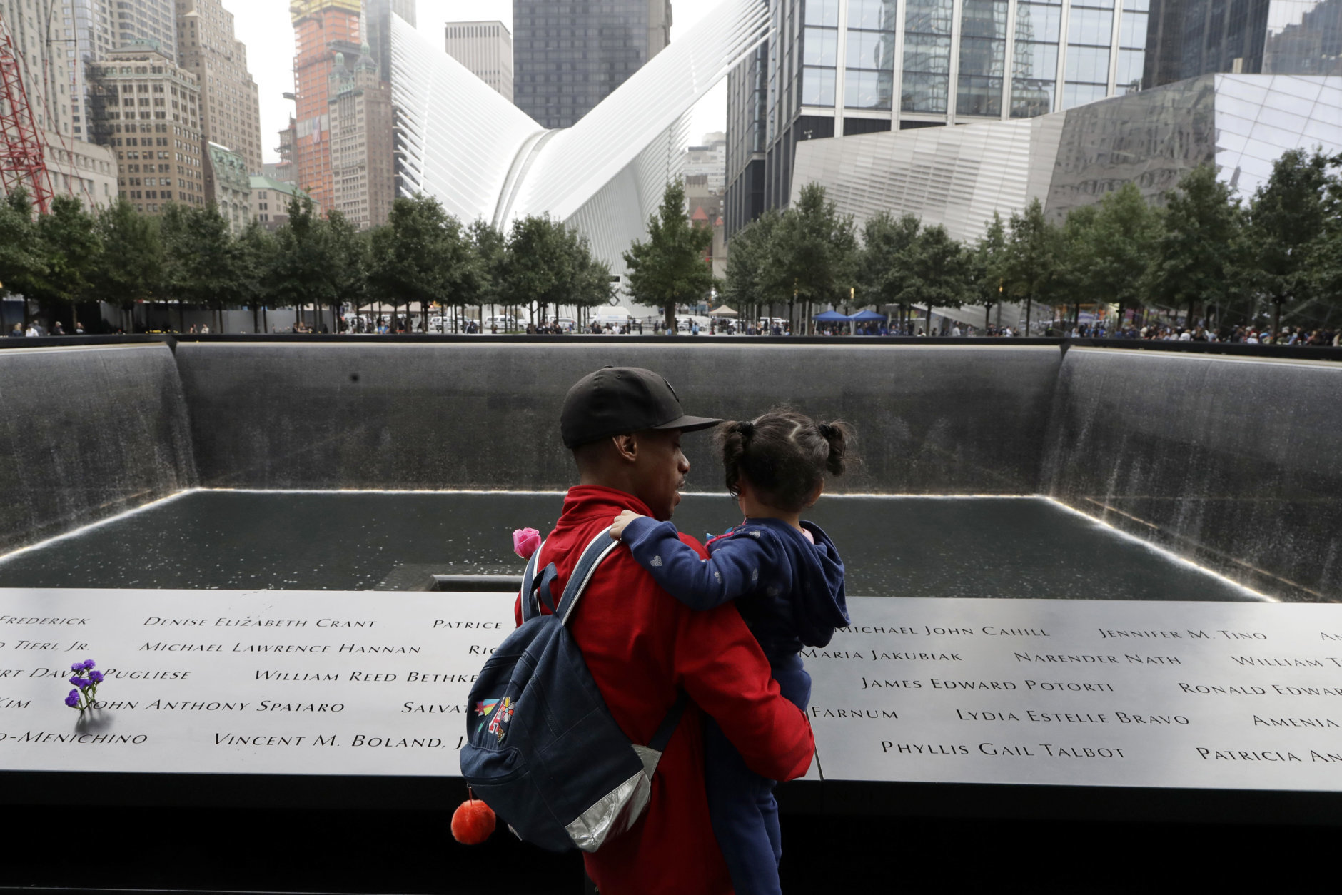 A man talks with a girl as they look at the North Pool at the World Trade Center during a ceremony marking the 17th anniversary of the terrorist attacks on the United States, Tuesday, Sept. 11, 2018, in New York. (AP Photo/Mark Lennihan)