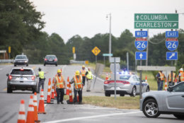 A South Carolina state trooper directs traffic as D.O.T. workers move cones at an access ramp to I-26 Tuesday, Sept. 11, 2018, in Columbia, S.C. A lane reversal was implemented earlier in the day, utilizing all lanes for travel west between Charleston and Columbia in anticipation of the arrival of Hurricane Florence. (AP Photo/Sean Rayford)