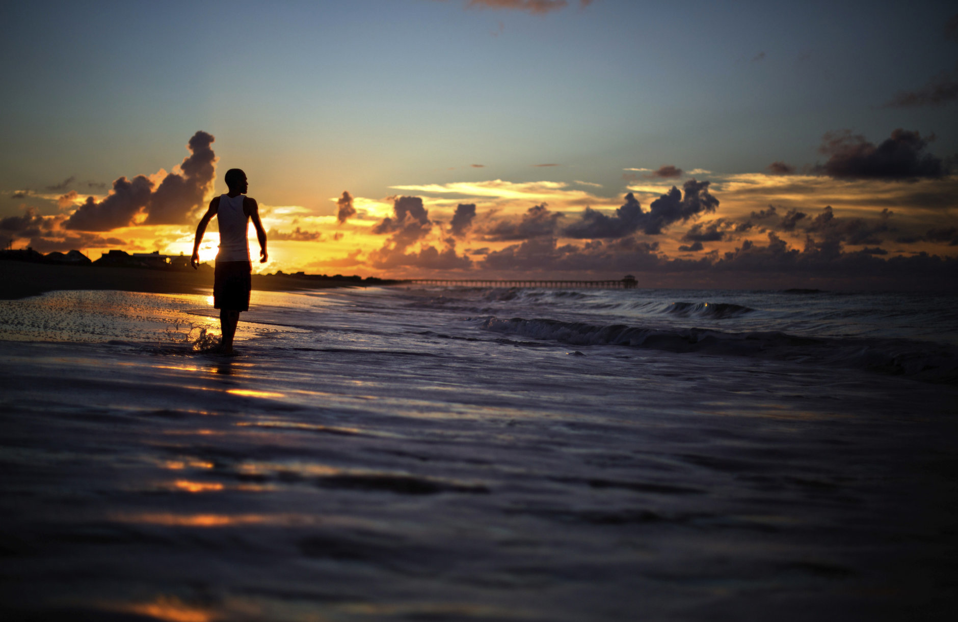 Andrew Lingle walks along the beach at sunrise as Hurricane Florence approaches the east coast in Atlantic Beach, N.C., Wednesday, Sept. 12, 2018. (AP Photo/David Goldman)
