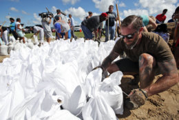 Brady Osborne ties freshly filled sandbags, Wednesday, Sept. 12, 2018, in Virginia Beach, Va., as Hurricane Florence moves towards the eastern shore. (AP Photo/Alex Brandon)