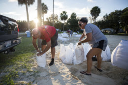 Filling sandbags with sand provided by the City of Tybee Island, Sib McLellan, left, and his wife, Lisa McLellan, prepare for Hurricane Florence, Wednesday, Sept., 12, 2018 on Tybee Island, Ga. (AP Photo/Stephen B. Morton)