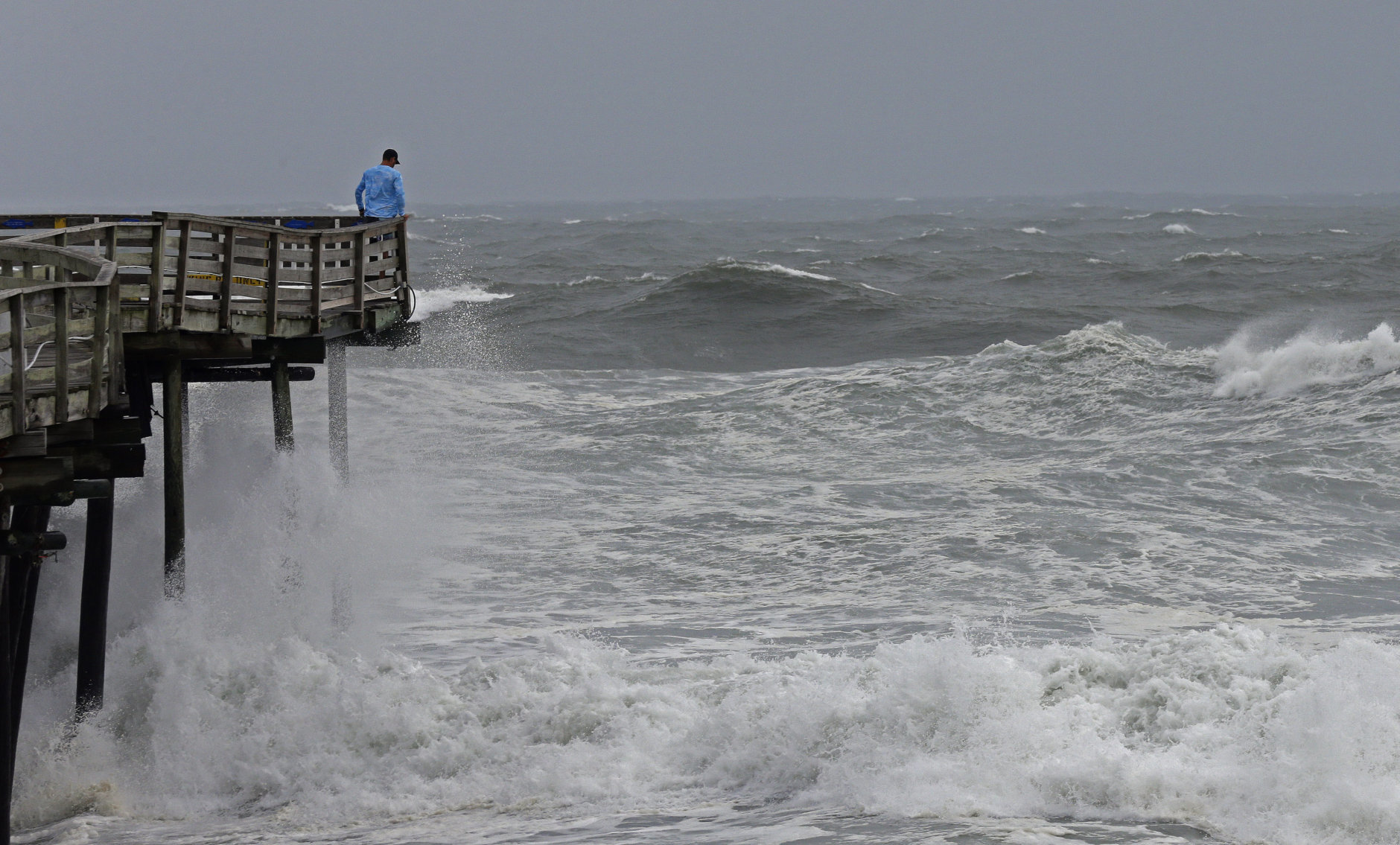 An onlooker checks out the heavy surf at the Avalon Fishing Pier in Kill Devil Hills, N.C., Thursday, Sept. 13, 2018 as Hurricane Florence approaches the east coast. (AP Photo/Gerry Broome)