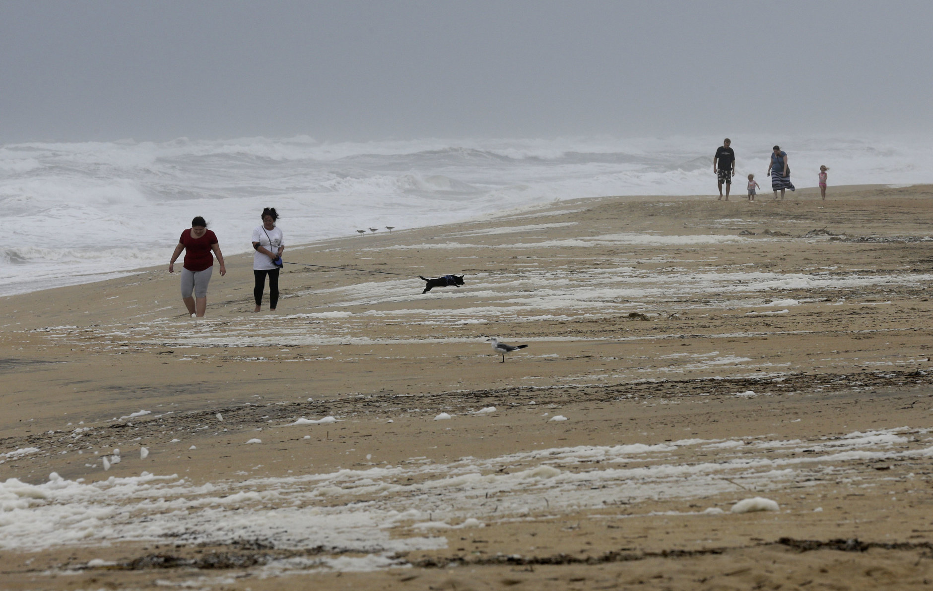 People walk the beach in Kill Devil Hills, N.C., Thursday, Sept. 13, 2018 as Hurricane Florence approaches the east coast. (AP Photo/Gerry Broome)