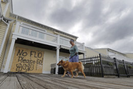 Barbara Timberlake walks with her dog Danny past a boarded up store on the river front in downtown Wilmington, N.C., as Hurricane Florence threatens the coast Thursday, Sept. 13, 2018. (AP Photo/Chuck Burton)