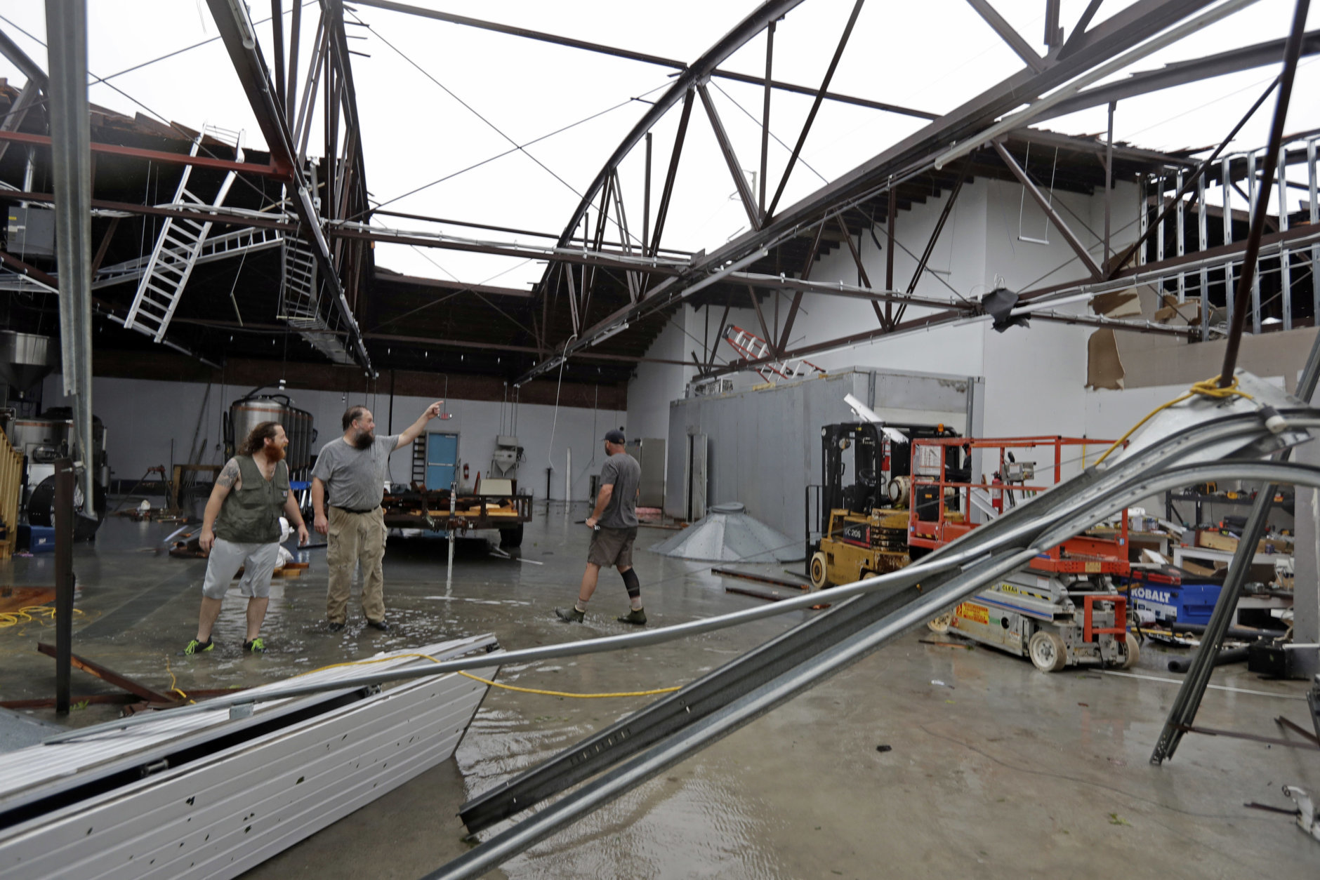 Ethan Hall, right, Michael Jenkins, center, and Nash Fralick, left, examine damage to Tidewater Brewing Co. in Wilmington, N.C., after Hurricane Florence made landfall Friday, Sept. 14, 2018. (AP Photo/Chuck Burton)