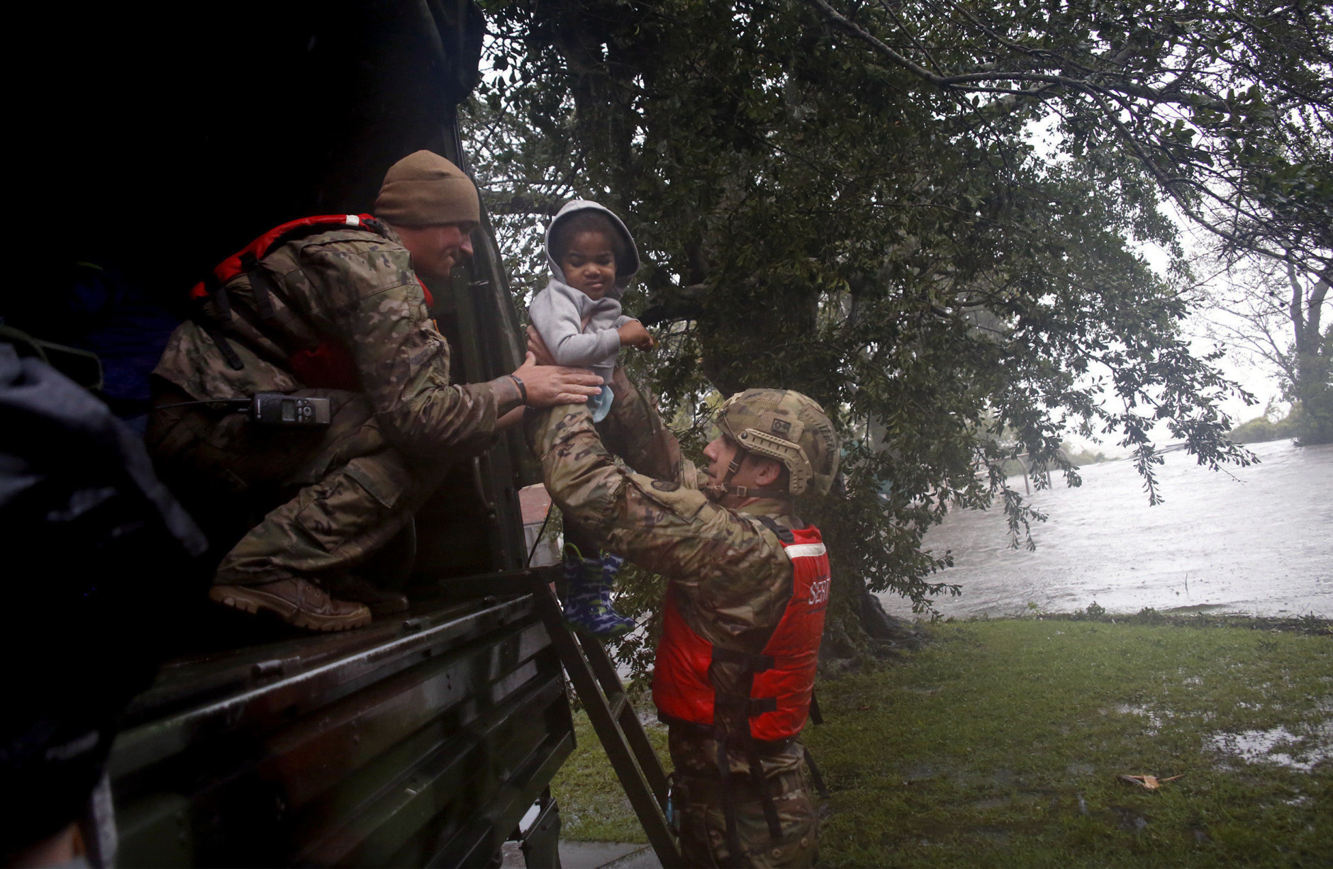 Rescue team members Sgt. Matt Locke, left, and Sgt. Nick Muhar, right, from the North Carolina National Guard 1/120th battalion, evacuates a family as the rising floodwaters from Hurricane Florence threatens their home in New Bern, N.C., on Friday, Sept. 14, 2018. (AP Photo/Chris Seward)