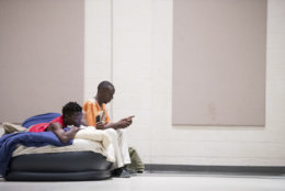 Eric Edwards Jr., left, and Elliott Farmer Jr. look at their phones from a blow up mattress at a storm shelter at Washington Street United Methodist Church as Florence slowly moves across the East Coast Friday, Sept. 14, 2018, in Columbia, S.C. Florence already has proven deadly with its nearly nonstop rain, surging seawater and howling winds, and the threat is days from ending as remnants of the hurricane slowly creep inland across the Carolinas. (AP Photo/Sean Rayford)
