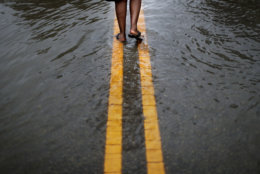 Helen McKoy walks down a flooded street in her neighborhood as Florence continues to dump heavy rain in Fayetteville, N.C., Sunday, Sept. 16, 2018. "I've never seen it like this before," said McCoy of the rising water down the street from her home. "Whatever God got for me he's going to give it to me. He said he's going to take care of us and that's what I'm going to have to live on." (AP Photo/David Goldman)