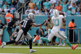 Miami Dolphins wide receiver Kenny Stills (10) catches a touchdown pass as he is pursued by Oakland Raiders defensive back Marcus Gilchrist (31) during the first half of an NFL football game, Sunday, Sept. 23, 2018, in Miami Gardens, Fla. (AP Photo/Brynn Anderson)