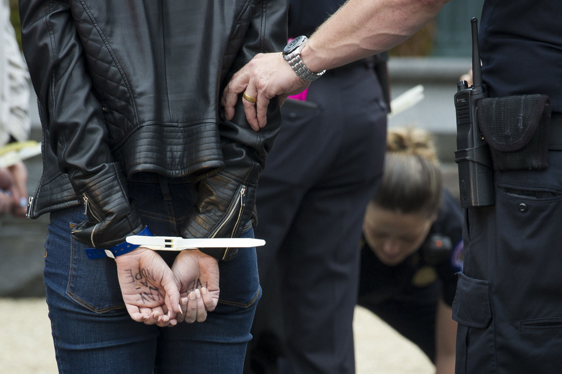 A supporter of Christine Blasey Ford, with "Kav-A-Nope" written on her hand is arrested for blocking traffic on the street between the Supreme Court and Capitol in Washington, Thursday, Sept. 27, 2018. T (AP Photo/Cliff Owen)
