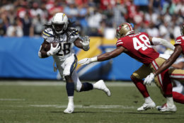 Los Angeles Chargers running back Melvin Gordon, left, fends off San Francisco 49ers linebacker Fred Warner during the first half of an NFL football game, Sunday, Sept. 30, 2018, in Carson, Calif. (AP Photo/Jae Hong)