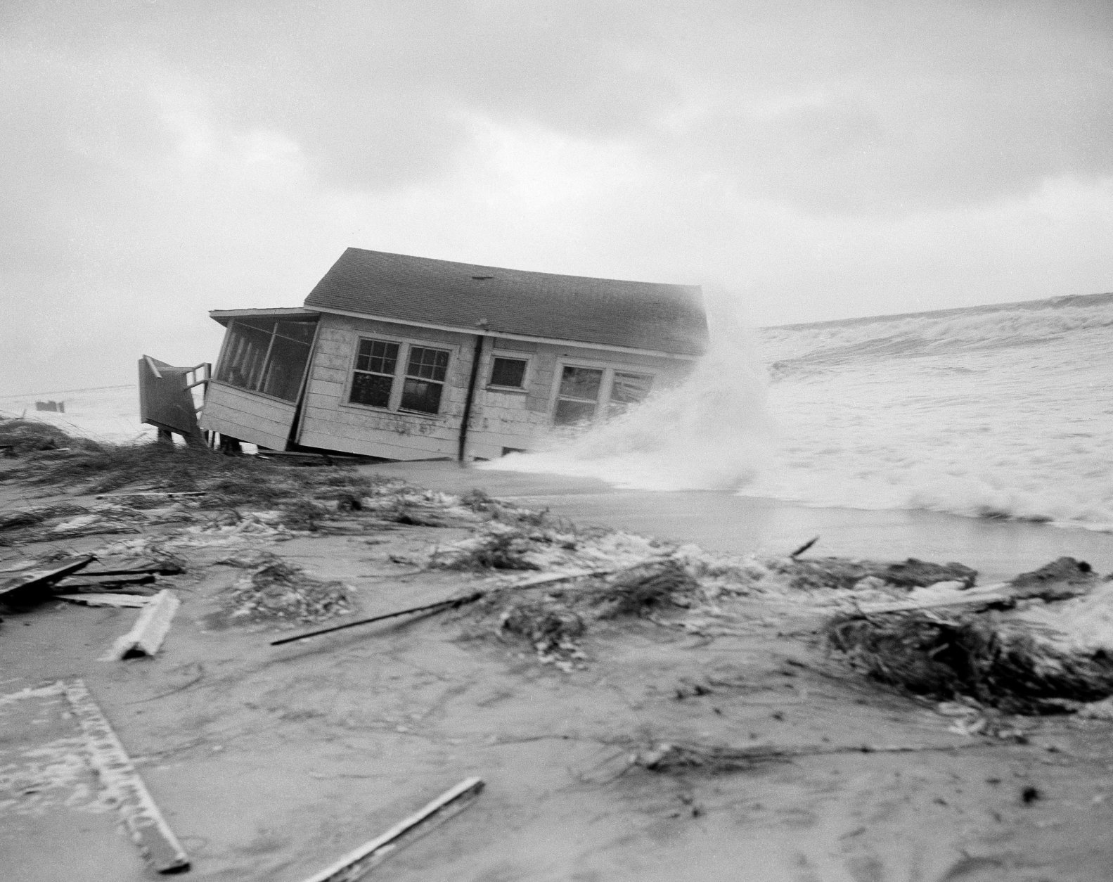 This tiny cottage, named the F. Maroon, that was badly damaged by hurricane Connie, gets a new treatment from hurricane Diane in Wilmington Beach, N.C., on August 17, 1955. Damage from Diane is not expected to be as great as Connie. (AP Photo)