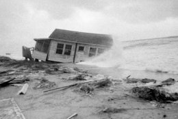 This tiny cottage, named the F. Maroon, that was badly damaged by hurricane Connie, gets a new treatment from hurricane Diane in Wilmington Beach, N.C., on August 17, 1955. Damage from Diane is not expected to be as great as Connie. (AP Photo)