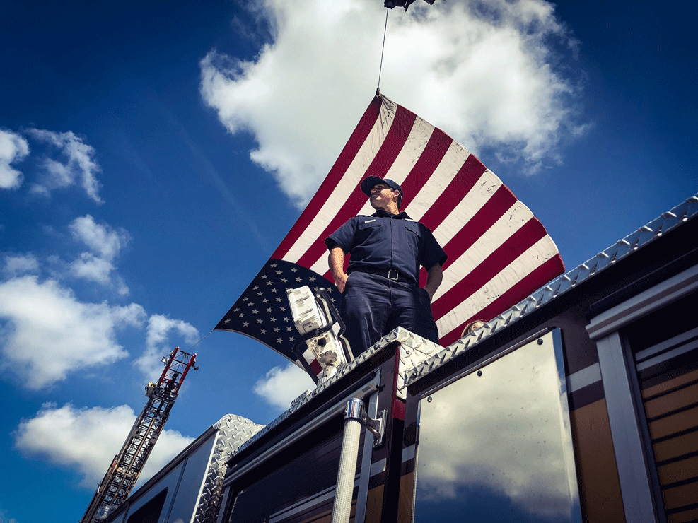 A firefighter waits on a bridge along Church Road above US 50 in Bowie, Maryland, for Sen. John McCain's funeral procession to pass on its way to the US Naval Academy in Annapolis, Maryland. (WTOP/Melissa Howell)