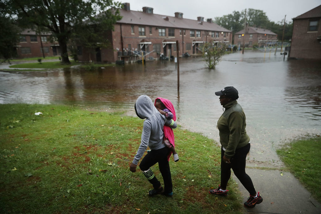 NEW BERN, NC - SEPTEMBER 13:  Diamond Dillahunt, 2-year-old Ta-Layah Koonce and Shkoel Collins survey the flooding at the Trent Court public housing apartments after the Neuse River topped its banks during Hurricane Florence September 13, 2018 in New Bern, United States. Coastal cities in North Carolina, South Carolina and Virginia are under evacuation orders as the Category 2 hurricane approaches the United States.  (Photo by Chip Somodevilla/Getty Images)