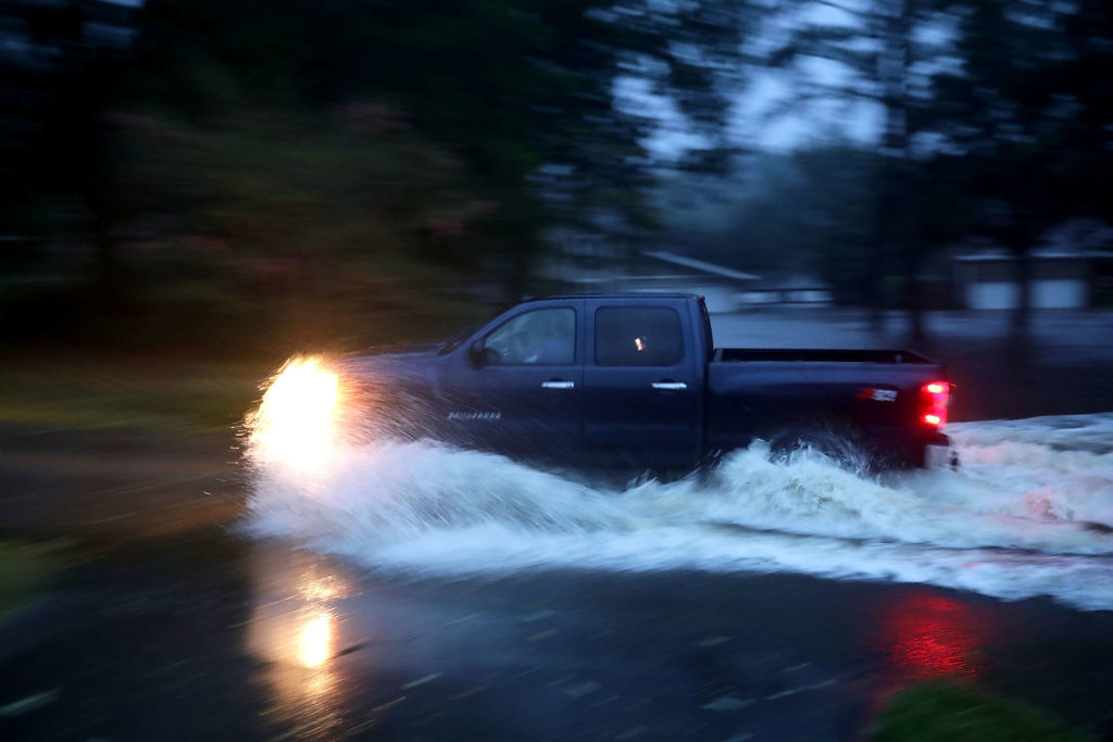 RIVER BEND, NC - SEPTEMBER 13:  A truck drives through deep water after the Neuse River went over its banks and flooded the street during Hurricane Florence September 13, 2018 in River Bend, North Carolina. Some parts of New Bern could be flooded with a possible 9-foot storm surge as the Category 2 hurricane approaches the United States.  (Photo by Chip Somodevilla/Getty Images)