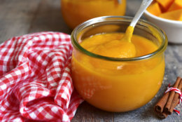 Pumpkin puree in a glass jar on a rustic wooden background.