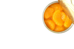 Closeup of an opened can of mandarin oranges on white background with copy space.