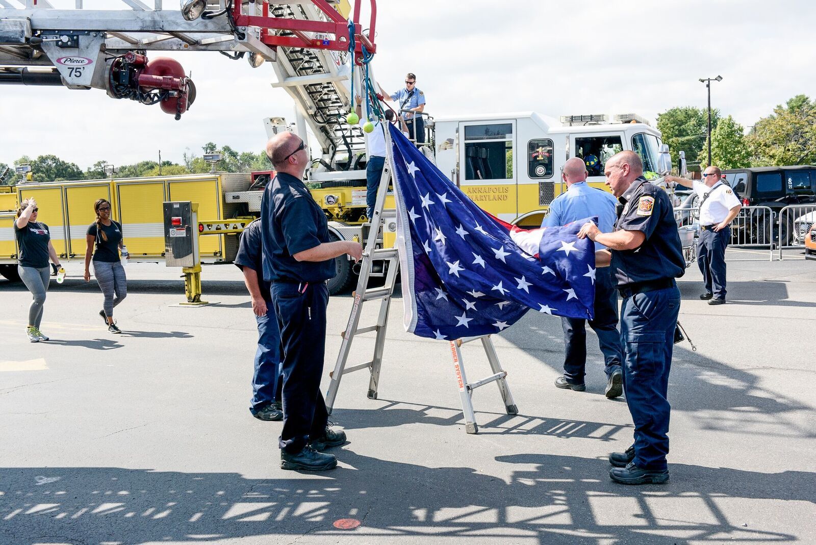 Members of the Annapolis Fire Department and the Naval District of Washington Fire Department Naval Academy Station work to put up the ladder arc flag. (Courtesy Megan Evans Photography)